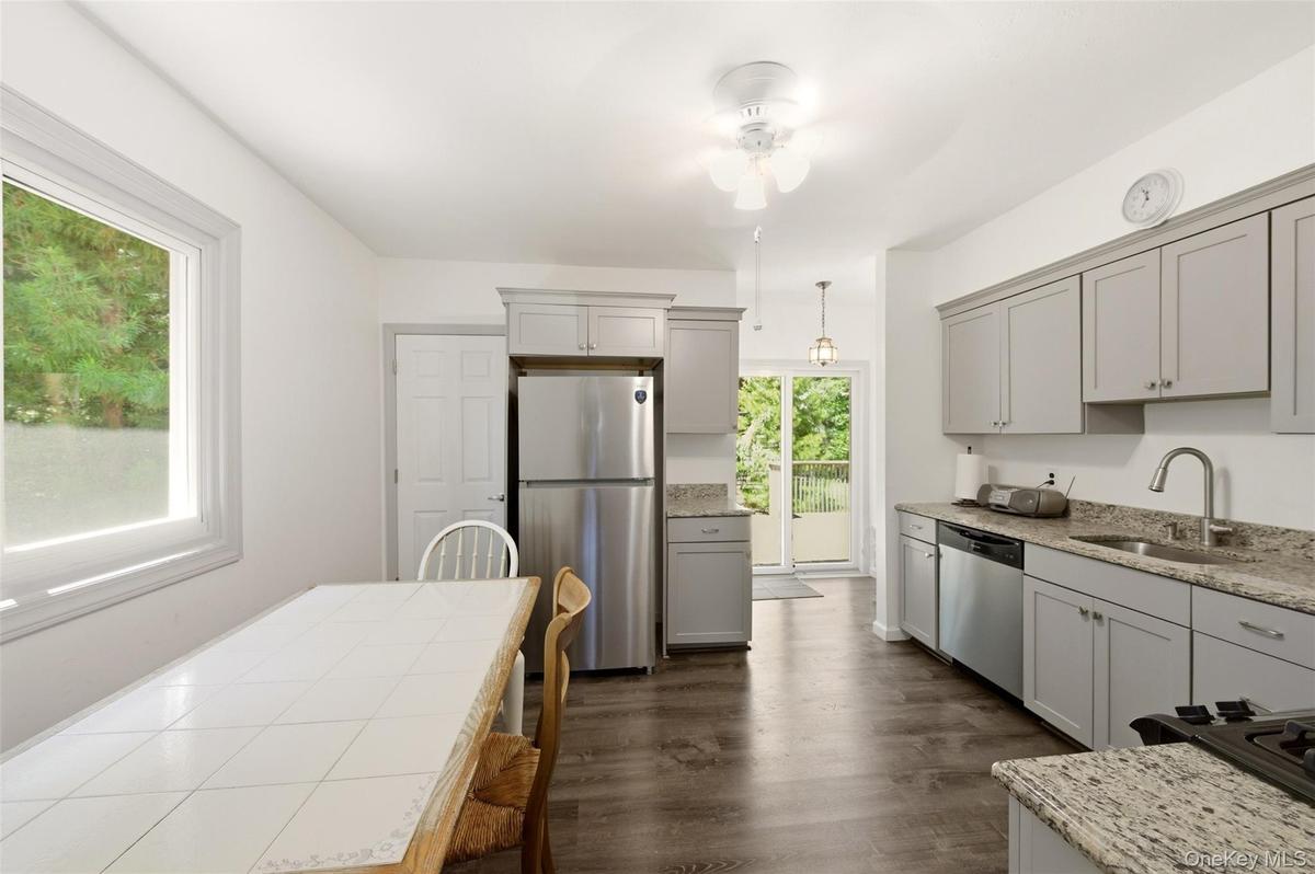 Kitchen featuring light gray cabinetry, stainless steel appliances, granite countertops, and wood-finish flooring