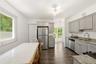 Kitchen featuring light gray cabinetry, stainless steel appliances, granite countertops, and wood-finish flooring