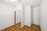 Room featuring wood-finish flooring, white walls, a ceiling fan, and sliding mirrored closet doors