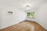 Room featuring wood-finish flooring, white crown molding, and baseboards