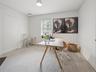 Bright office featuring a window with white blinds, neutral wall paint, and textured flooring