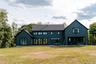 Rear view of house featuring board and batten siding, a lawn, and a patio