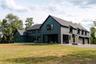 Rear view of property with board and batten siding, a shingled roof, a yard, and a patio