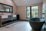 Full bath with double vanity, a freestanding tub, and vaulted ceiling