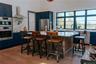 Kitchen with tasteful backsplash, blue cabinetry, wall chimney exhaust hood, appliances with stainless steel finishes, and light wood-type flooring