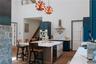 Kitchen featuring dark wood finished floors, light stone counters, wine cooler, wall chimney range hood, and a center island