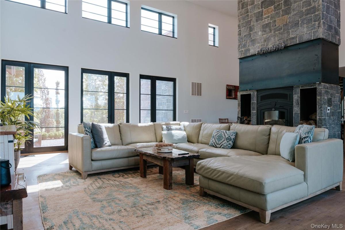 Living area featuring a high ceiling, a glass covered fireplace, and wood finished floors