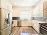 Modern kitchen featuring stainless steel appliances, white cabinetry, wood-finish flooring, and a subway tile backsplash