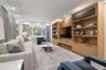 Living room featuring custom built-in wood cabinetry and shelving, recessed lighting, expansive windows with custom automated treatments, leading to o