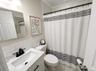 Bathroom featuring a modern vanity with integrated sink, quartz-finish countertop, and matte black faucet