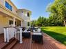 Expansive outdoor living area featuring a multi-level composite deck, white baluster railings, and a covered porch