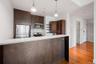 Kitchen featuring dark wood-finish cabinetry, stainless steel appliances, white tile backsplash, and light-colored countertop