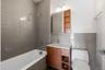 Bathroom featuring a bathtub with overhead shower, grey subway tile surround, wood-finish vanity with countertop sink, wall-mounted mirror with integr