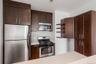 Kitchen featuring dark wood-finish cabinetry, stainless steel appliances, and a mosaic tile backsplash