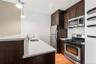 Modern kitchen featuring dark wood-finish cabinetry, stainless steel appliances, white quartz countertops, and a subway tile backsplash