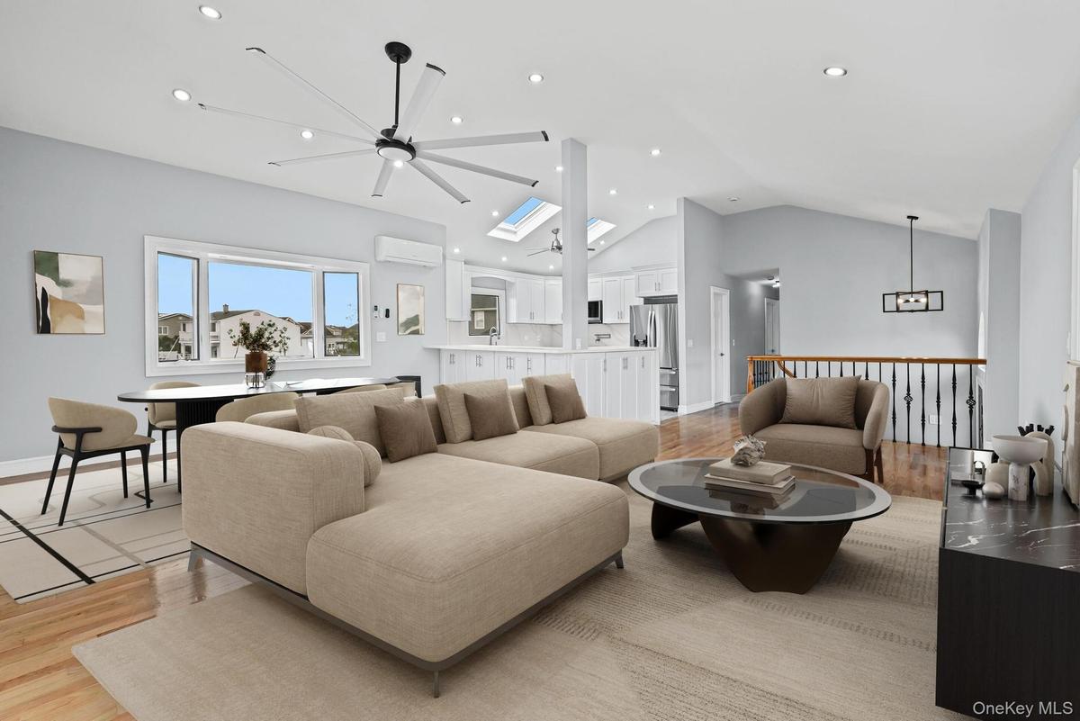 Living room featuring light wood-type flooring, lofted ceiling, ceiling fan, a skylight, and recessed lighting