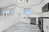 Kitchen with appliances with stainless steel finishes, white cabinets, tasteful backsplash, recessed lighting, and a skylight