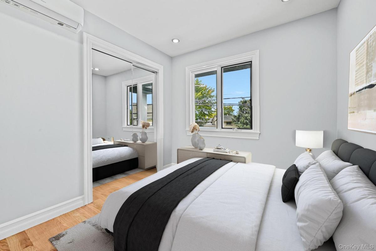 Bedroom with wood finished floors, a wall mounted air conditioner, recessed lighting, and a closet