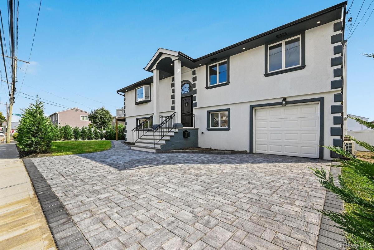 View of front facade featuring stucco siding, a garage, and decorative driveway