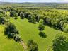 Beyond this large, fenced field is the wooded part of the property for trail riding, hiking, or additional fields or infrastructure