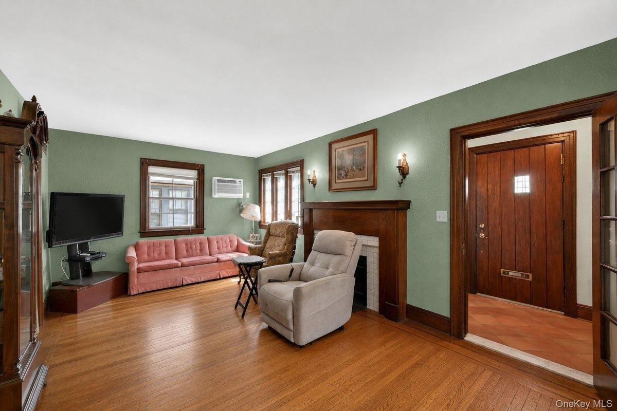 Inviting living area featuring wood-finish flooring, a wood-trimmed fireplace, and sage green walls