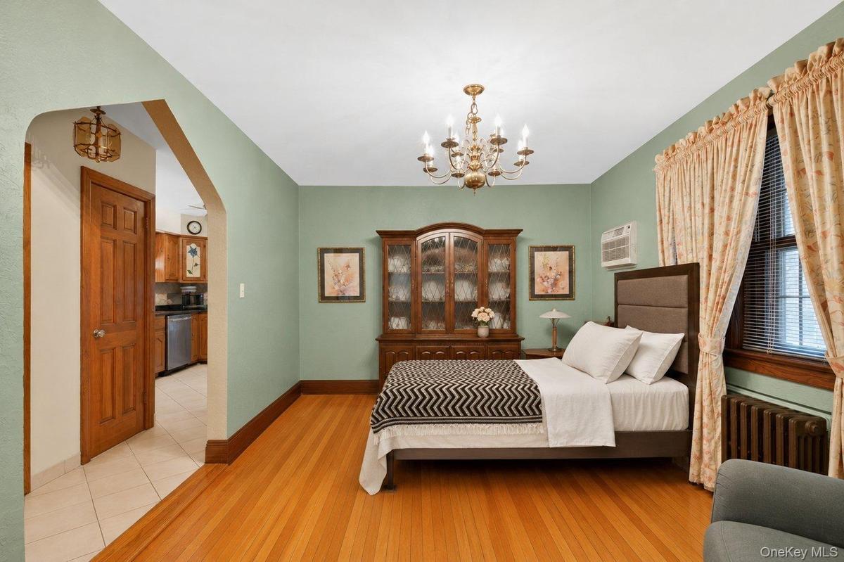 Hardwood flooring throughout, complemented by a brass chandelier and detailed window trim