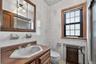 Bathroom featuring ceramic tile walls with subtle floral accents, a wood-finish vanity with an integrated sink, a medicine cabinet with mirror panels,