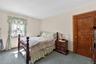 Bedroom featuring a window with natural light, light-toned walls, and a wood-finish door with matching trim