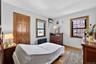 Room featuring wood-finish flooring, two windows with wood trim, a built-in radiator, a paneled wood door, and white walls
