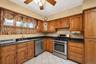 Kitchen featuring solid wood cabinetry, black countertops, a stainless steel range, stainless steel dishwasher, and a white tile floor