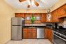 Kitchen featuring wood cabinetry, stainless steel appliances, dark countertops, and a tiled backsplash