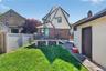 Rear exterior featuring a grass lawn, a small elevated deck with sliding glass doors, a brick patio, and a separate stucco-finished structure with a b