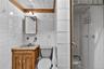 Bathroom featuring white tile walls, a wood vanity with a gray sink, a mirrored medicine cabinet, and a glass-enclosed shower with a chrome showerhead