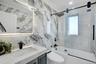 Full bath with crown molding, bath / shower combo with glass door, vanity, tile walls, and stone wall