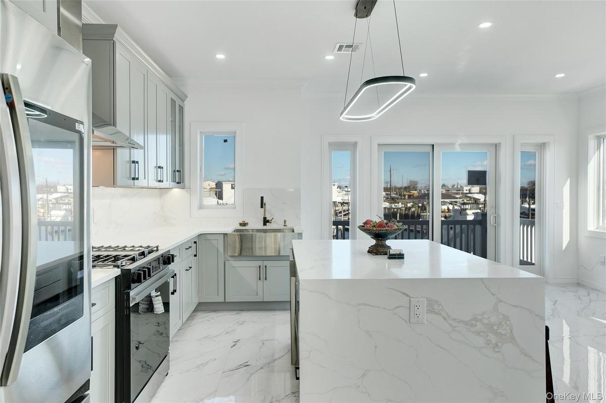 Kitchen featuring light marble finish floors, stainless steel refrigerator, light stone counters, pendant lighting, and recessed lighting
