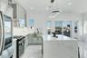 Kitchen featuring light marble finish floors, stainless steel refrigerator, light stone counters, pendant lighting, and recessed lighting