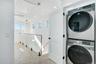 Laundry room featuring attic access, stacked washer and clothes dryer, and recessed lighting