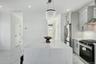 Kitchen with light marble finish floors, gas stove, wall chimney range hood, ornamental molding, and light stone counters