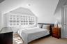 Carpeted bedroom featuring a baseboard heating unit and vaulted ceiling