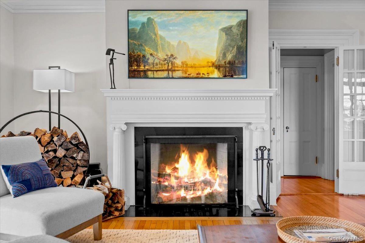 Detailed view of ornamental molding, wood finished floors, and a fireplace