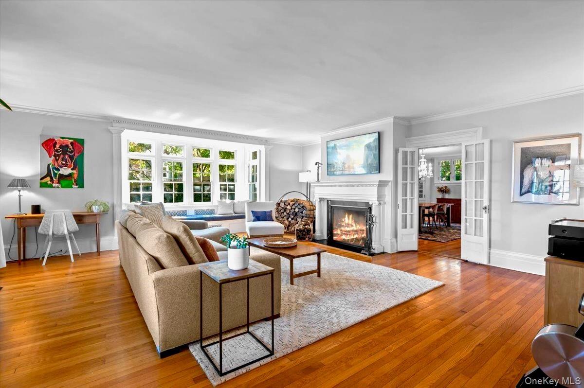 Living area with a fireplace , french doors, light wood-type flooring, and ornamental molding