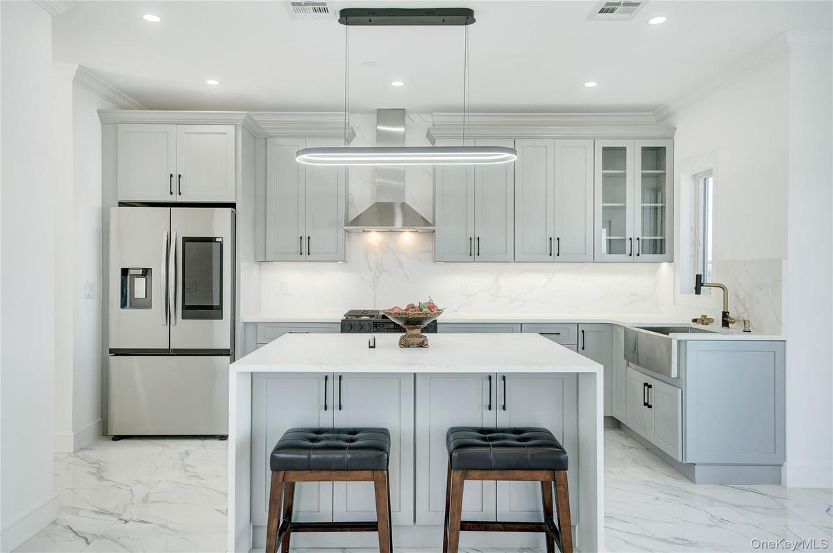 Kitchen featuring stainless steel refrigerator with ice dispenser, light stone countertops, glass insert cabinets, a breakfast bar, and a kitchen isla
