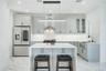 Kitchen featuring stainless steel refrigerator with ice dispenser, light stone countertops, glass insert cabinets, a breakfast bar, and a kitchen isla