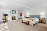 Bedroom with carpet, beam ceiling, a warm lit fireplace, and crown molding