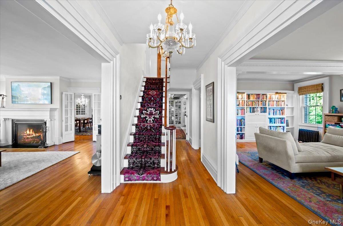 Entrance foyer featuring a chandelier, ornamental molding, hardwood / wood-style floors, stairway, and a fireplace