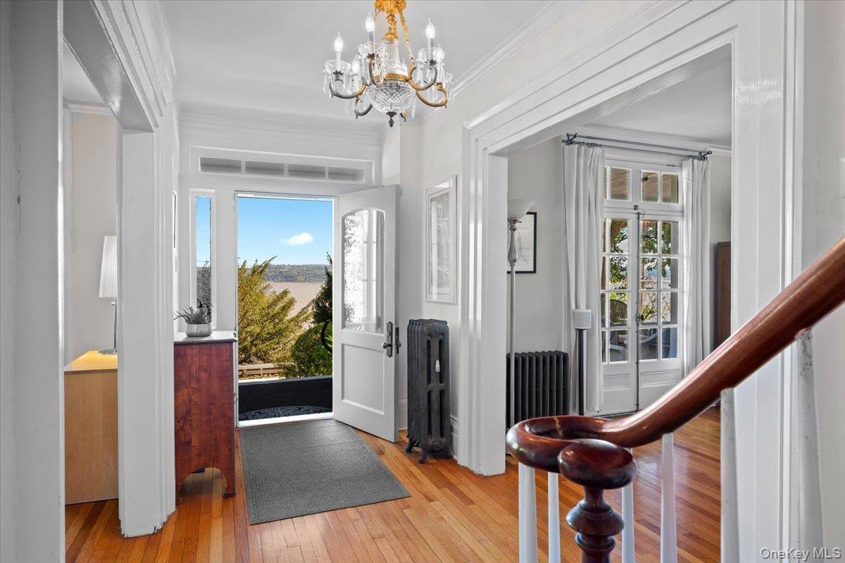 Foyer with light wood-style flooring, radiator heating unit, a chandelier, and ornamental molding