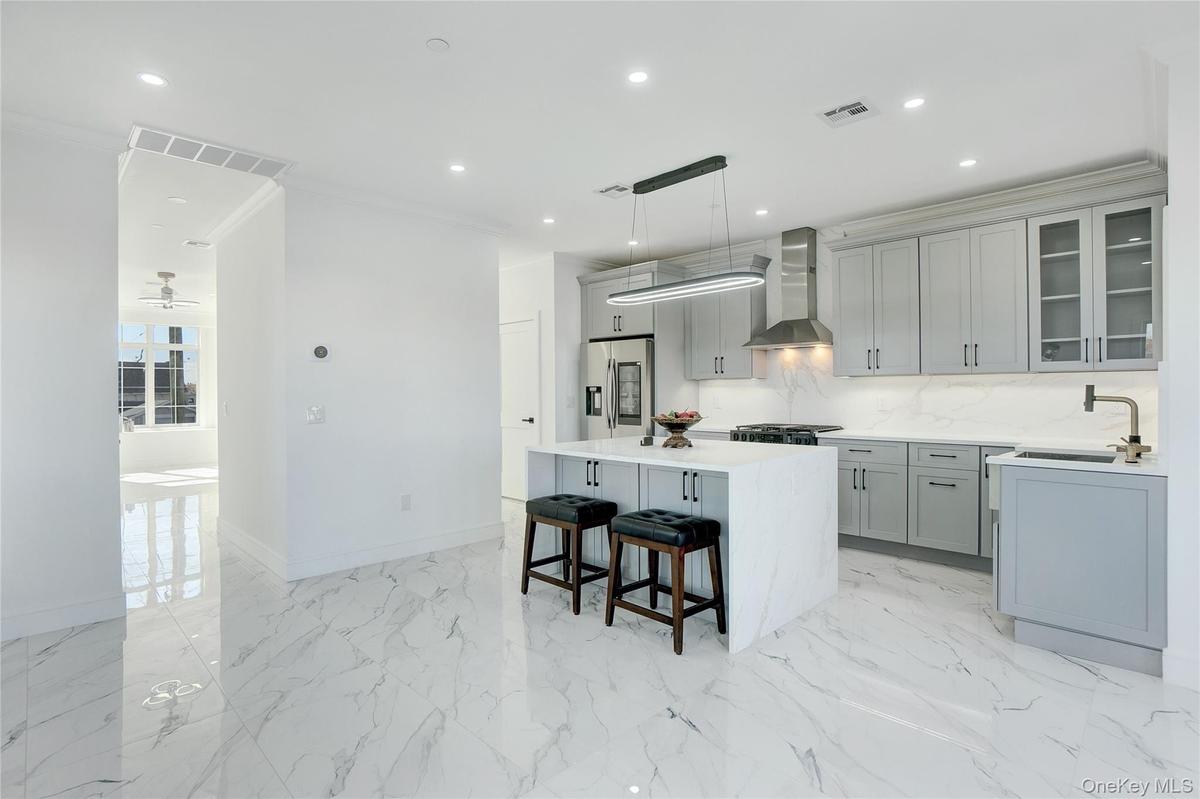 Kitchen featuring ornamental molding, a center island, glass insert cabinets, hanging light fixtures, and gray cabinets