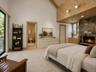 Spacious and inviting primary suite featuring soaring cathedral ceilings and a beautiful stone fireplace that adds warmth and charm. Sliding glass doo