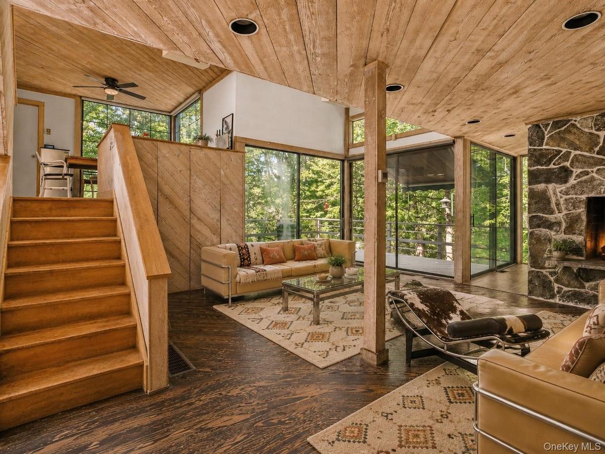Spacious Living room with cathedral ceilings, floor to ceiling windows, sliding glass doors and a beautiful stone fireplace