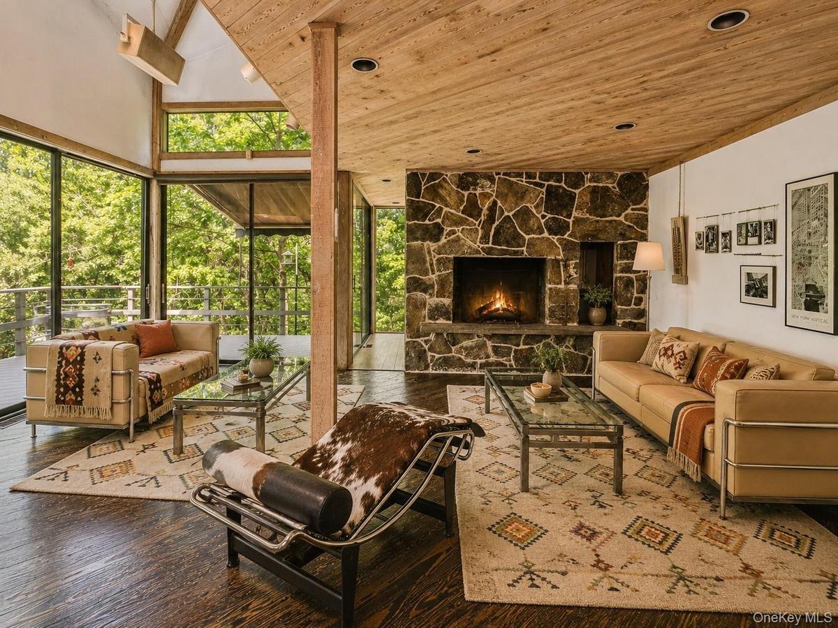 Spacious Living room with cathedral ceilings, floor to ceiling windows, sliding glass doors and a beautiful stone fireplace